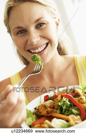 Stock Photo - Mid Adult Woman Eating A Healthy Salad. Fotosearch