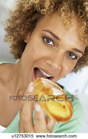 Stock Photography - Mid Adult Woman Eating A Pastry. Fotosearch