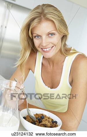Stock Image - Mid Adult Woman Eating Cereal With Fruit. Fotosearch