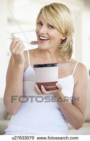 Stock Photo - Mid Adult Woman Eating Chocolate Ice-Cream And Smiling At The Camera. Fotosearch