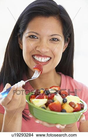 Picture - Mid Adult Woman Eating Fresh Fruit Salad. Fotosearch