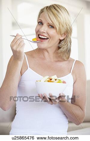Stock Photograph - Mid Adult Woman Eating Fresh Fruit Salad. Fotosearch