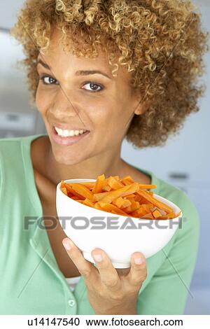 Stock Image - Mid Adult Woman Holding A Bowl Of Carrots. Fotosearch