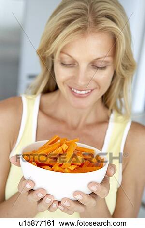Stock Image - Mid Adult Woman Holding A Bowl Of Carrots. Fotosearch