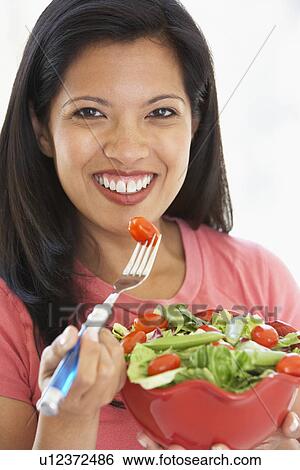 Stock Photograph - Mid Adult Woman Holding A Bowl Of Salad, Smiling At The Camera. Fotosearch