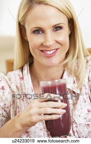 Stock Photo - Mid Adult Woman Holding A Fresh Berry Smoothie. Fotosearch