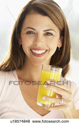 Mid Adult Woman Holding A Glass Of Orange Juice, Smiling At The Camera View Large Photo Image Stock Photo - Mid Adult Woman Holding A Glass Of Orange Juice, Smiling At The Camera. Fotosearch