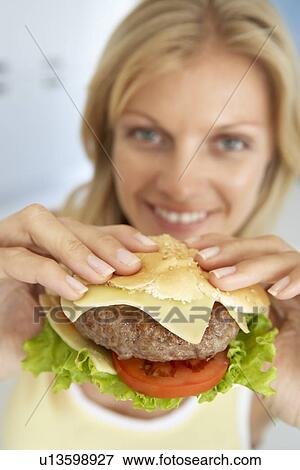 Mid Adult Woman Holding A Hamburger, Smiling At The Camera View Large Photo Image Stock Photo - Mid Adult Woman Holding A Hamburger, Smiling At The Camera. Fotosearch