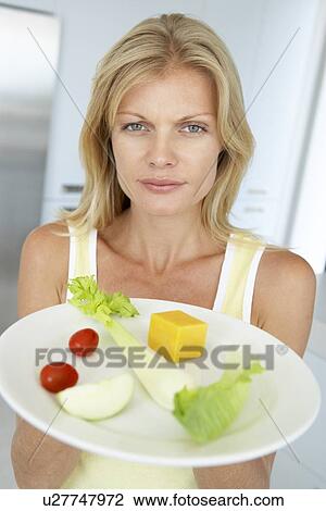 Stock Image - Mid Adult Woman Holding A Plate Of Healthy Food. Fotosearch