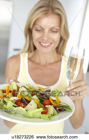 Stock Photograph - Mid Adult Woman Holding A Wine Glass And Fresh Salad. Fotosearch