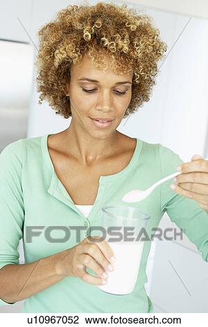 Stock Image - Mid Adult Woman Holding Dietary Supplements. Fotosearch