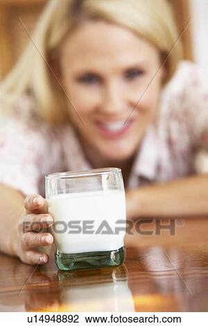 Stock Image - Mid Adult Woman Holding Glass Of Milk, Smiling At Camera. Fotosearch