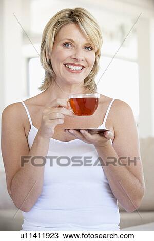 Mid Adult Woman Holding Tea Cup And Smiling At Camera View Large Photo Image Stock Image - Mid Adult Woman Holding Tea Cup And Smiling At Camera. Fotosearch
