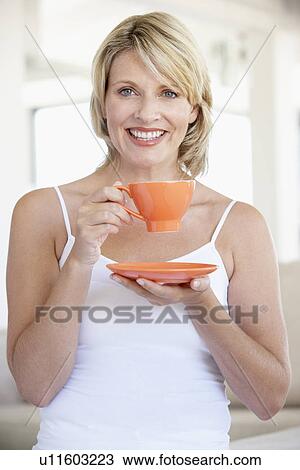 Mid Adult Woman Holding Tea Cup And Smiling At Camera View Large Photo Image Stock Image - Mid Adult Woman Holding Tea Cup And Smiling At Camera. Fotosearch