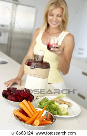 Picture - Mid Adult Woman Making Fresh Vegetable Juice. Fotosearch