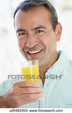 Stock Image - Middle Aged Man Drinking Fresh Orange Juice. Fotosearch