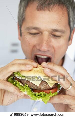 Stock Photo - Middle Aged Man Eating A Burger. Fotosearch
