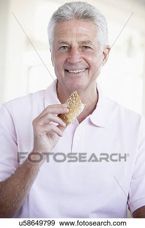 Stock Photo - Middle Aged Man Eating Brown Bread Roll. Fotosearch