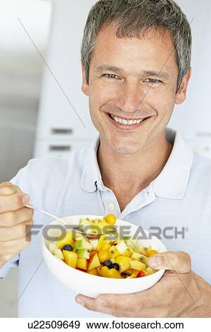 Stock Photo - Middle Aged Man Eating Fresh Fruit Salad. Fotosearch
