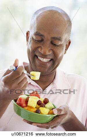 Stock Photograph - Middle Aged Man Eating Fresh Fruit Salad. Fotosearch