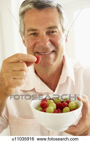 Stock Photograph - Middle Aged Man Eating Fresh Fruit. Fotosearch