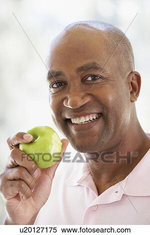 Middle Aged Man Eating Green Apple And Smiling At The Camera View Large Photo Image Stock Photography - Middle Aged Man Eating Green Apple And Smiling At The Camera. Fotosearch