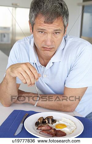 Stock Photograph - Middle Aged Man Eating Unhealthy Fried Breakfast. Fotosearch