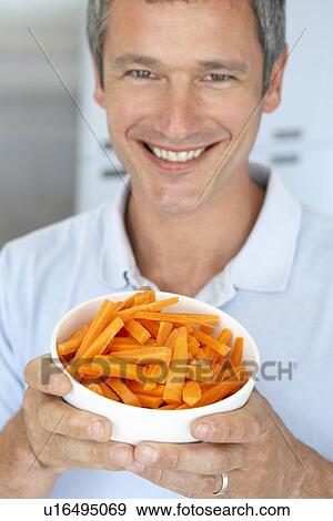 Stock Photo - Middle Aged Man Holding A Bowl Of Carrots. Fotosearch