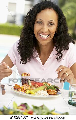 Stock Image - Middle Aged Woman Dining Al Fresco. Fotosearch