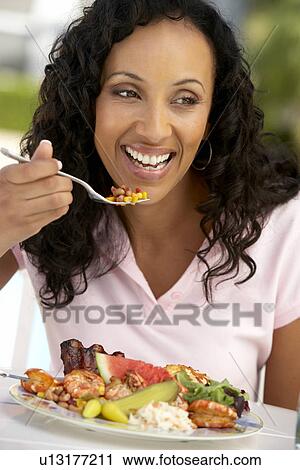 Stock Image - Middle Aged Woman Dining Al Fresco. Fotosearch