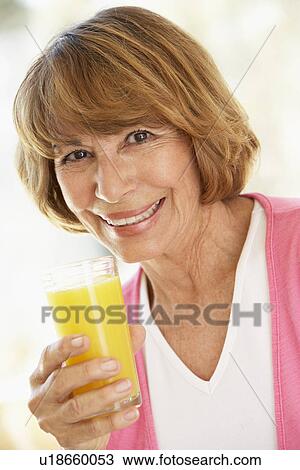 Stock Image - Middle Aged Woman Drinking Fresh Orange Juice. Fotosearch