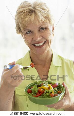 Stock Image - Middle Aged Woman Eating Fresh Salad. Fotosearch