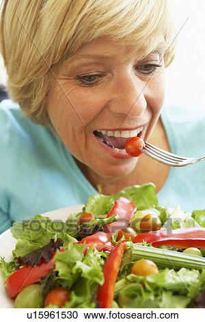 Stock Image - Middle Aged Woman Eating Healthy Salad. Fotosearch