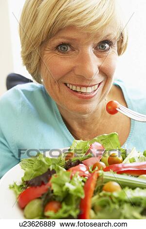 Stock Photo - Middle Aged Woman Eating Healthy Salad. Fotosearch