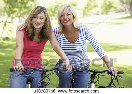 Stock Photograph - Mother And Daughter Cycling Through A Park. Fotosearch