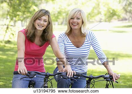 Stock Photography - Mother And Daughter Cycling Through A Park. Fotosearch