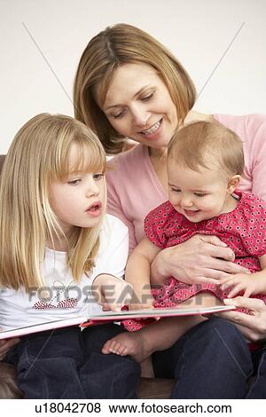 Stock Photo - Mother And Daughters Reading Book. Fotosearch