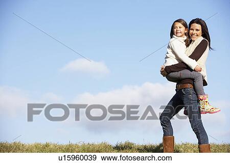 Stock Photo - Mother Carrying Her Daughter. Fotosearch