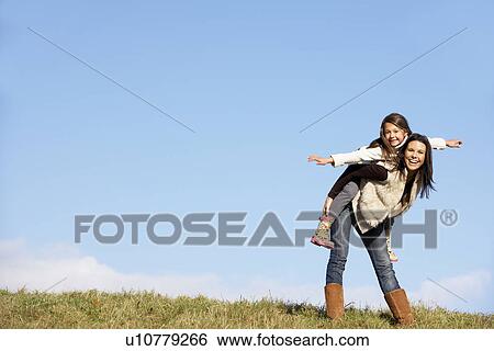 Mother Giving Her Daughter A Piggy Back Ride View Large Photo Image Stock Photograph - Mother Giving Her Daughter A Piggy Back Ride. Fotosearch