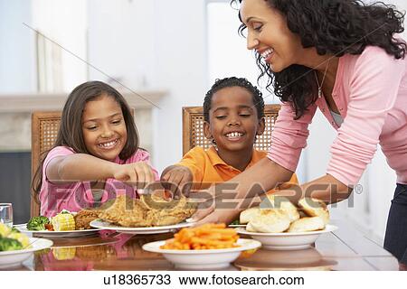 Stock Image - Mother Serving A Meal To Her Children At Home. Fotosearch