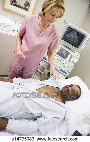 Stock Photo - Nurse Checking On Patient Lying On Hospital Bed. Fotosearch