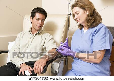 Stock Image - Nurse Giving Patient Injection Through Tube. Fotosearch