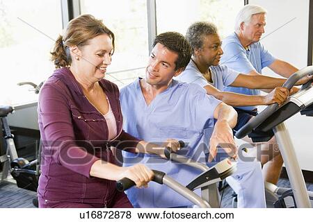 Stock Photo - Nurse With Patient In Rehabilitation Using Exercise Machine. Fotosearch