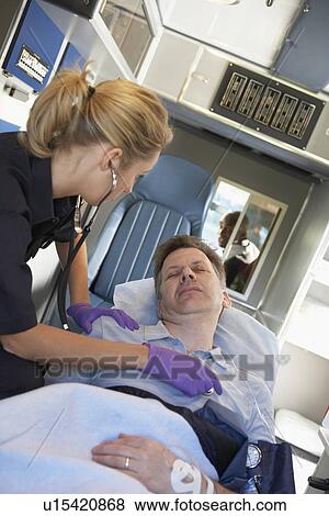 Stock Photo - Paramedic attending to patient in ambulance. Fotosearch