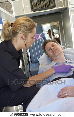 Stock Photo - Paramedic attending to patient in ambulance. Fotosearch