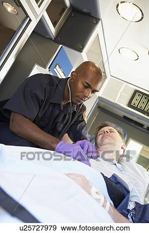 Stock Photo - Paramedic attending to patient in ambulance. Fotosearch