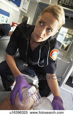 Stock Photography - Paramedic holding oxygen mask over patient's face. Fotosearch