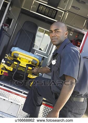 Stock Image - Paramedic removing empty gurney from ambulance. Fotosearch