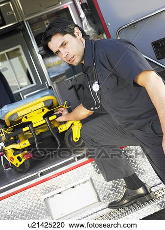Stock Image - Paramedic removing empty gurney from ambulance. Fotosearch