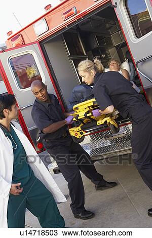 Stock Image - Paramedics and doctor unloading patient from ambulance. Fotosearch